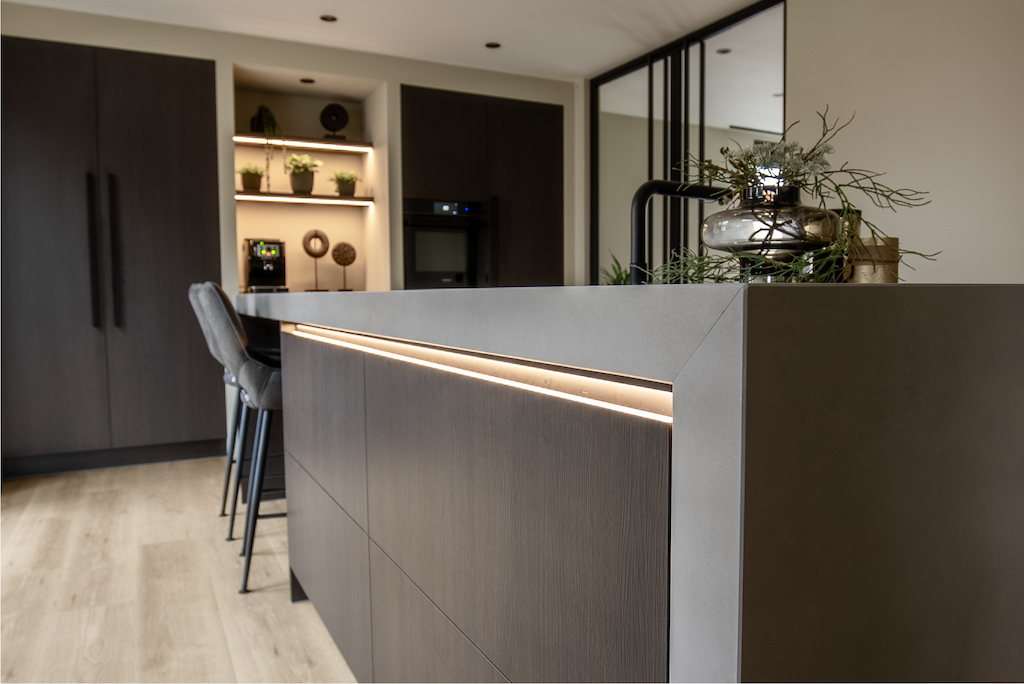 Donkere keuken op maat met betonlook werkblad en ledverlichting onder het blad